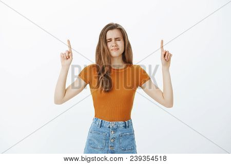 Intense Nervous Attractive Woman In Stylish Outfit, Raising Index Fingers And Pointing Up With Close