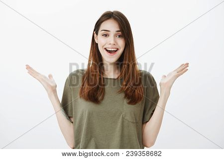 Positive Friendly Pretty Brunette Smiling Broadly And Raising Palms High, Being Surprised With Aweso