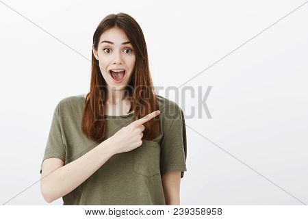 Portrait Of Happy Good-looking Caucasian Female Student In Casual Outfit, Pointing At Upper Right Co