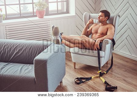 Handsome Shirtless Muscular Man Lying On The Chair, Drink Cup Of Tea, Resting After A Hard Workout A