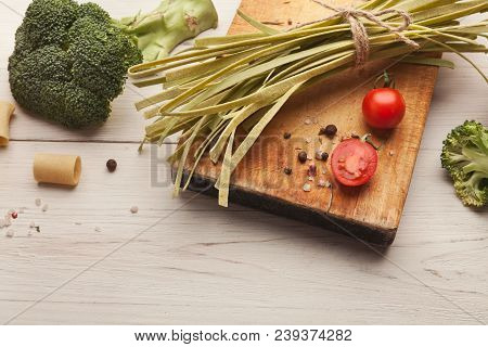 Raw Handmade Green Tagliatelle With Spinach Juice, Broccolli, Tomatoes And Spices On White Wooden Ta
