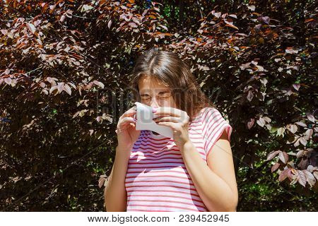 Front View Of A Single Girl Sneezing And Blowing In A Wipe Outdoors With A Green Background