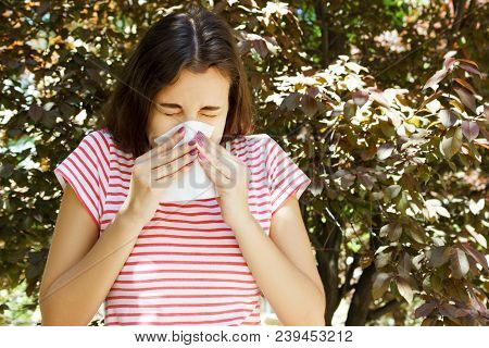 Front View Of A Single Girl Sneezing And Blowing In A Wipe Outdoors With A Green Background