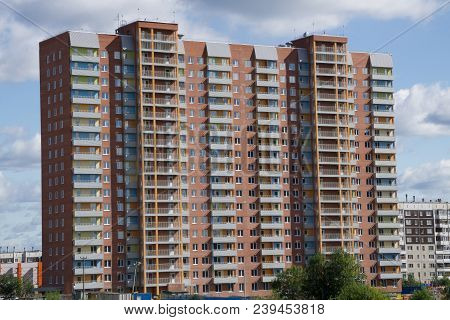 A Multi-storey Brick Building Under Construction, Against A Blue Sky Background. High Multi-story Bu