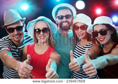 Happy young people showing OK sign in the night beach party
