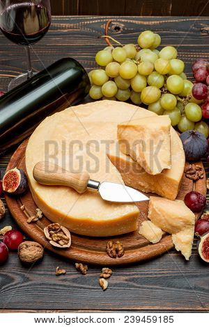 Whole Round Head Parmesan Cheese, Wine And Grapeson Wooden Cutting Board