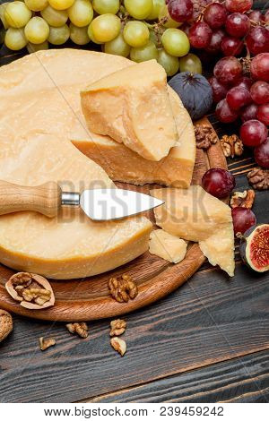 Whole Round Head Parmesan Cheese And Grapes On Wooden Cutting Board