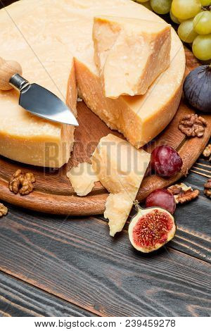 Whole Round Head Parmesan Cheese And Grapes On Wooden Cutting Board