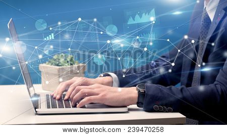 Businessman typing on laptop with linked reports charts grapghs around