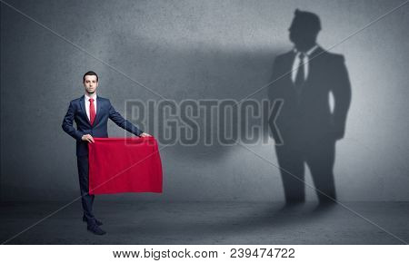 Businessman standing with red cloth on his hand and his shadow on the background