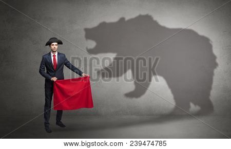 Businessman standing with red cloth in his hand and big bear shadow on his background