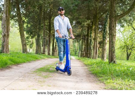 Man Using Blue Electric Scooter In The Park