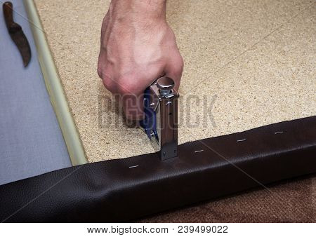 Handy Man Upholstering Paricle Board Using Brown Leather, Staples And Blue Stapler