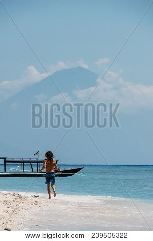 Man Runnning Beach With White Sand On Mountain Background With Clouds At Top