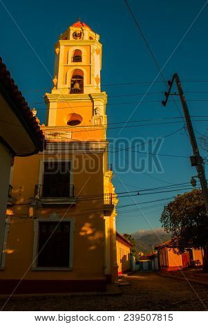 Trinidad, Cuba. The Bell Tower Of San Francisco De Asis Against The Blue Sky. Street In The Center O