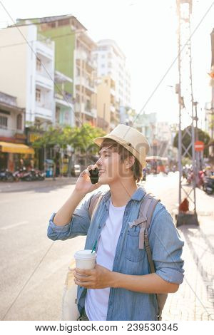 Smiling Handsome Young Man Drinking Coffee And Using Smart Phone