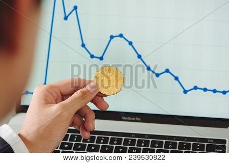 Man Holding Bitcoin And Background With Smart Phones, Laptops And Business Graphs - Concepts For Sta