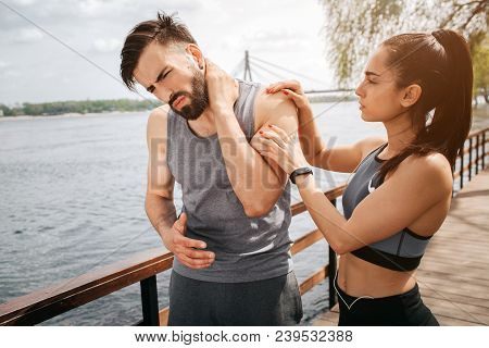 Young Man Has A Pain In The Neck. He Has Put A Hand On The Place Where The Pain Is. His Girlfriend H