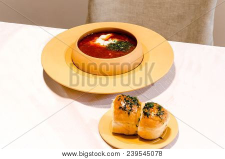 Red Soup With Rolls On White Table