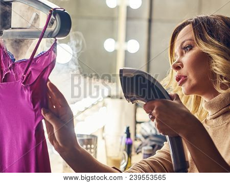 A Yong Woman Is Preparing For An Event, She Is Ironing Her Dress.