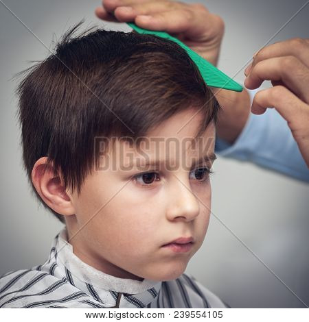 Boy Getting Haircut By Hairdresser In Barbershop.