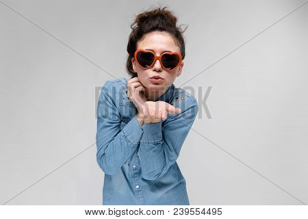 Young Girl With Glasses In Heart On Gray Background. Portrait Of A Young Beautiful Girl. Charming Gi