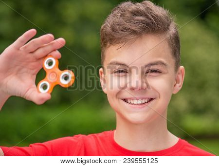 Young Teen Boy Holding Popular Fidget Spinner Toy - Outdoors Portrait. Happy Smiling Child Playing W