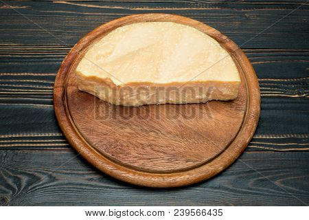 Pieces Of Parmesan Or Parmigiano Hard Cheese On Wooden Cutting Board