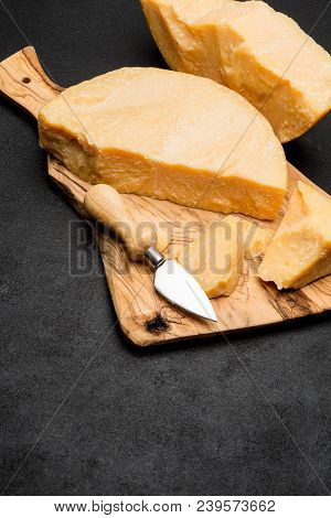Pieces Of Parmesan Or Parmigiano Hard Cheese And Grapes On Wooden Cutting Board