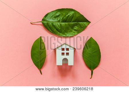 Miniature Toy Model House With Green Leaves On Pink Pastel Colourful Trendy Backgdrop. Eco Village, 