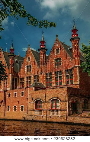 Trees And Brick Buildings On The Canal Edge In A Sunny Day At Bruges. With Many Canals And Old Build