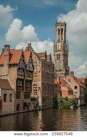 Old Brick Buildings And Belfry On The Canal Edge In A Sunny Day At Bruges. With Many Canals And Old 