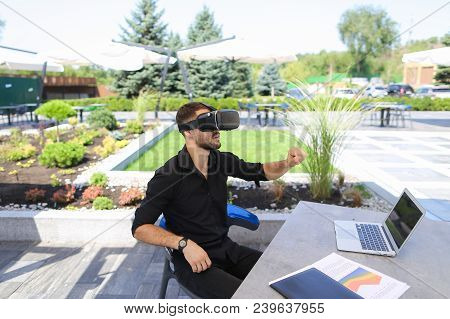 Man Working With Papers And Laptop, Enjoying Virtual Reality Glasses In Open Air . Conceptof Working