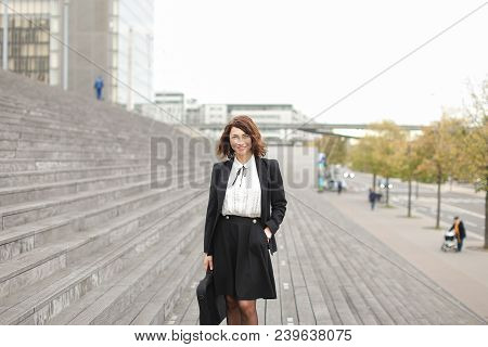 European Female Manager Standing On Stairs Outside In High Buildings Background. Concept Of Professi