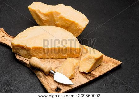Pieces Of Parmesan Or Parmigiano Hard Cheese And Grapes On Wooden Cutting Board