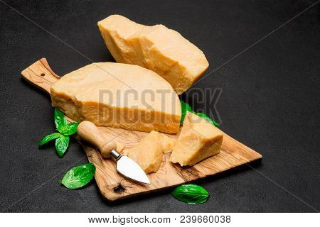 Pieces Of Parmesan Or Parmigiano Hard Cheese And Grapes On Wooden Cutting Board