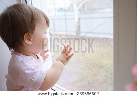 Child Looking Out The Window Longing For Some Sunshine  Because Of Rain. Curiosity Childness. Curiou