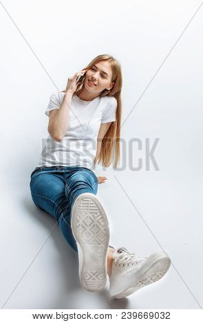 Beautiful Young Girl Talking On The Phone, In The Studio, Isolated Background, Cheerful And Positive