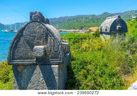 The Close-up Of Ancient Stone Tombs Of Lycian Necropolis, Standing On The Green Slope Of The Hill In