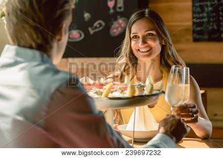 Happy young couple in love toasting with champagne during romantic dinner with seafood as oysters and crabs at the restaurant