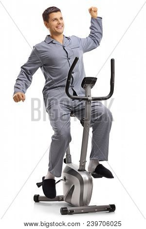 Young man in pajams stretching himself on an exercise bike isolated on white background