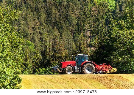 Field And Operation Of The Tractor. Wind And Dust Over Workers. Red Tractor On A Field. Agricultural