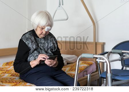 Lonley Elderly 95 Years Old Woman Sitting At The Bad Using Modern Mobile Phone Application To Monito