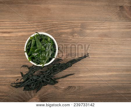 Heap Of Dry Wakame Seaweed On Wooden Background. Healthy Algae Food With Place For Text