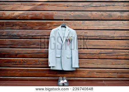 Stylish Elegant Wedding Groom Suit With Buttonhole Hanging On Wooden Background, Copy Space. Gray Su