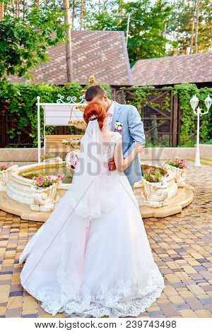 Happy Groom And Beautiful Redhead Bride In White Dress Dancing Outdoors, Free Space. Beautiful Weddi
