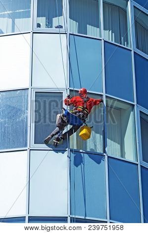 Rope Access Technician In A Helmet Washes The Window Of A High-rise Building From The Outside, Hangi