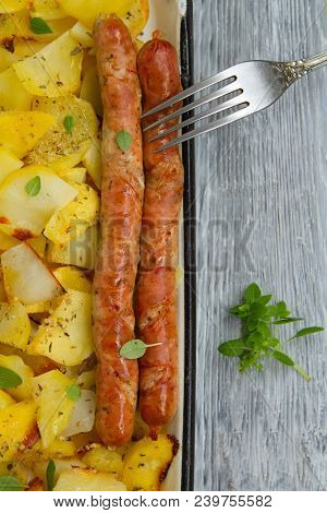 Tasy Baked Potato Slices With Fried Munich Sausages With Basil Leaves On A Baking Sheet
