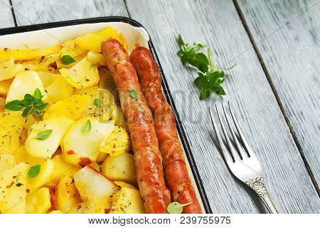 Tasy Baked Potato Slices With Fried Munich Sausages With Basil Leaves On A Baking Sheet