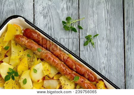 Tasy Baked Potato Slices With Fried Munich Sausages With Basil Leaves On A Baking Sheet